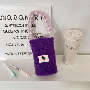 Close-up of fuzzy purple lamb wool bottle bag with checkered handle and cat patch