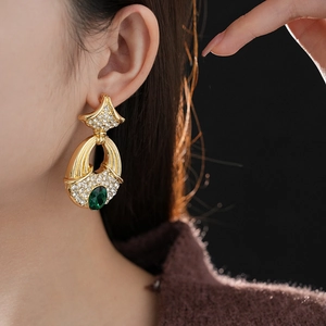 Detail of vintage gold earrings with emerald green stone and sparkling rhinestones
