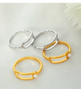 Detail view of gold and silver double-layered rings with elegant pearls on fabric