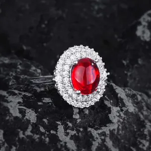 Polished silver ring with oval ruby gemstone and double halo zircons on black stone