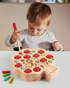 Toddler playing with magnetic wooden apple tree catching game to improve fine motor skills