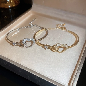 Detail of heart-shaped adjustable open bangles in gold and silver with sparkling zircon stones