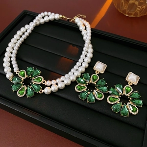 Dettaglio della collana di perle a doppio strato e orecchini a fiore verde
