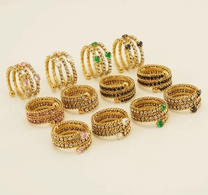 Detailed view of multi-layered gold woven rings with heart-shaped colorful gemstones