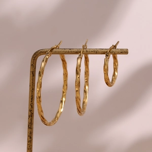 Three sizes of 18K gold plated twisted hoop earrings on a minimalist metal display stand