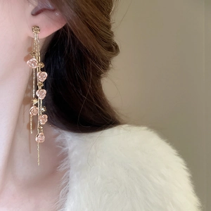 Détail de boucles d'oreilles pampilles dorées avec fleurs roses 3D sur un mannequin
