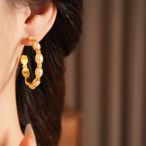 Dettaglio macro di orecchini a cerchio vintage con perle e placcatura in oro indossati
