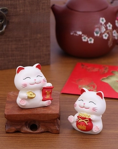 Detailed view of two cute Maneki Neko resin kittens with gold ingots and lucky charms