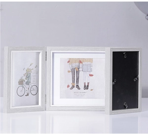 Detail view of a triple folding Nordic wood picture frame with metal hinges and back clips