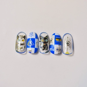 Detail of Egyptian theme nail art stickers featuring gold cats and Eye of Horus icons