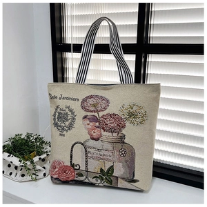 Detail of floral tapestry tote bag with French script and striped woven handles