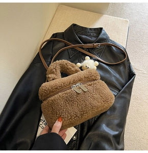 Close-up of brown faux shearling crossbody bag with zipper and plush pompom accessory