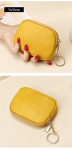Detail of yellow pebbled leather coin purse with golden zipper and metal keychain