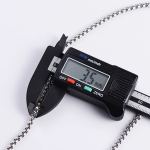Macro detail of digital caliper measuring a 3.5mm thick stainless steel box chain