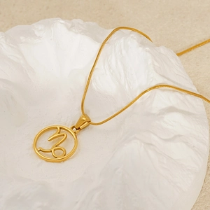 Detailed macro of gold Capricorn zodiac sign cutout pendant on sleek snake chain