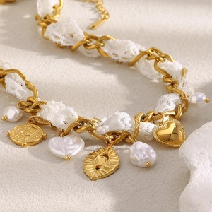 Detailed close-up of 18K gold chain intertwined with white lace and vintage charms