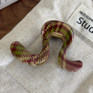 Détail d'une pince à cheveux ondulée avec motif à carreaux rouge et vert sur toile