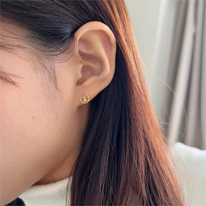 Elegant gold pretzel-shaped stud earrings with sparkling central zircon on model
