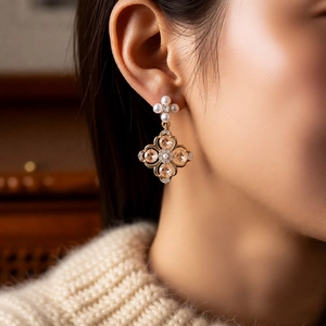 Close-up of vintage flower earrings with pearls and amber stones on model's ear