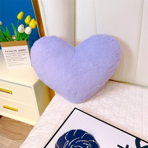 Détail d'un coussin cœur en peluche violette avec texture douce en fausse fourrure