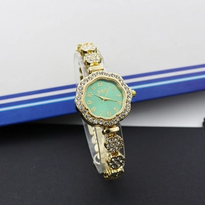Détail de la montre dorée pour femme avec cadran carré vert et ornements strass