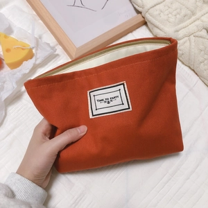 Orange houndstooth canvas makeup bag with Time to Party label and zipper closure
