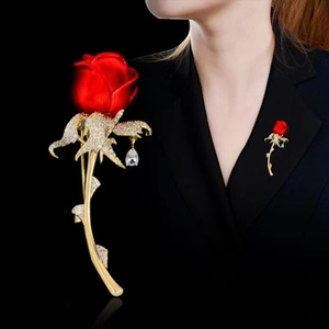 Detailansicht einer roten Rosenbrosche mit Goldblättern und ein Modell, das sie an einem Blazer trägt