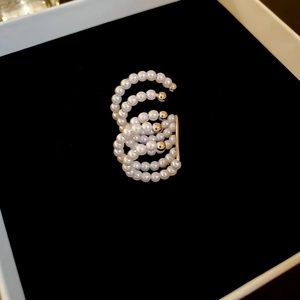 Detailed close-up of multilayer pearl ear cuffs with gold metal accents on black velvet