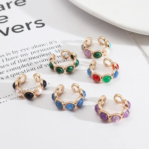 Ensemble de bagues dorées avec pierres naturelles colorées et perles sur fond blanc