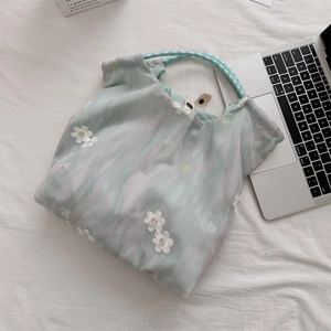 Detailed close-up of mint green tulle tote bag with floral embroidery and braided handles