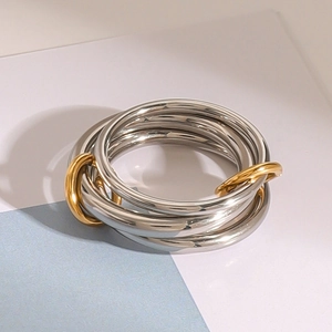 Macro detail of interlocking silver and gold bands with a polished mirror finish