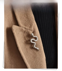 Silver snake brooch with sparkling crystals pinned on a camel wool coat collar