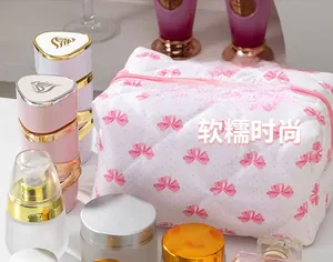 Gros plan d'une trousse de maquillage blanche matelassée avec nœuds roses et zip