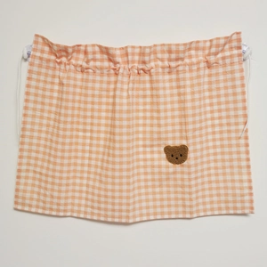 Detail of orange checkered sunshade curtain featuring a cute brown bear embroidery