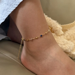Detail of gold ankle bracelet with colorful star charms on a woman's ankle