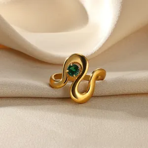 Macro view of gold wave ring with a green gemstone on satin background