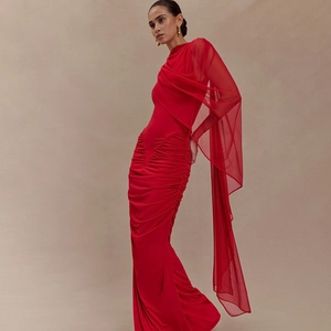 Detail view of red asymmetrical pleated dress with one-sided mesh sleeve and silk texture