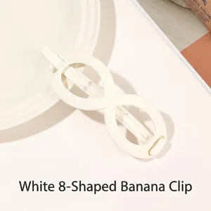 Close-up of matte white infinity shaped hair claw clip on a minimalist ceramic plate