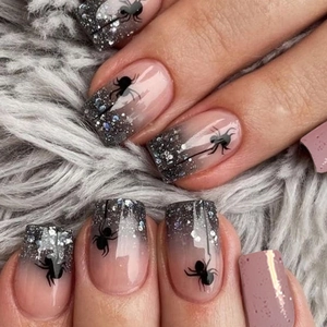 Nahaufnahme von Nude-Gradient-Nägeln mit schwarzem Glitzer und Spinnenmuster