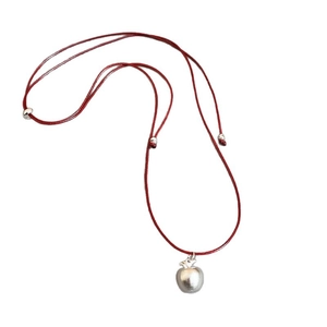 Minimalist red leather cord necklace featuring a matte silver apple pendant with adjustable bead