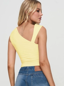 Détail d'un haut en tricot asymétrique jaune et d'un jean en denim bleu ajusté