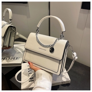 Detail of white PU leather crossbody bag with silver metal chain and round charm