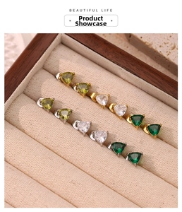 Detail of triangle cut zircon stud earrings in gold and silver settings on velvet display