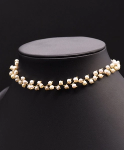Detail view of dainty freshwater pearls and gold wire on a black neck mannequin