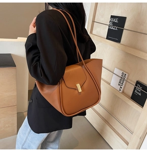Gros plan du sac à bandoulière en cuir marron avec boucle dorée dans un décor naturel