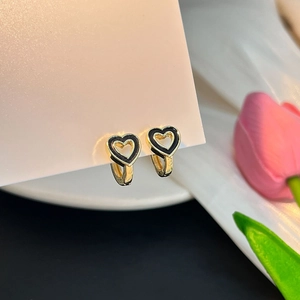 Détail de boucles d'oreilles cœur dorées avec émail noir sur une carte d'affichage