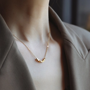 Collar de oro minimalista con cuentas hexagonales usado por una modelo al cuello