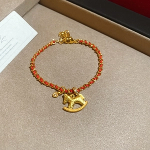 Dettaglio del bracciale intrecciato rosso con ciondolo a cavallo dorato e cuore