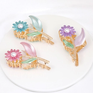 Close-up of golden flower hair claws with pastel enamel petals and pearl centers
