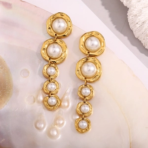 Détail de boucles d'oreilles perles dorées à cinq maillons sur fond coquillage et corail